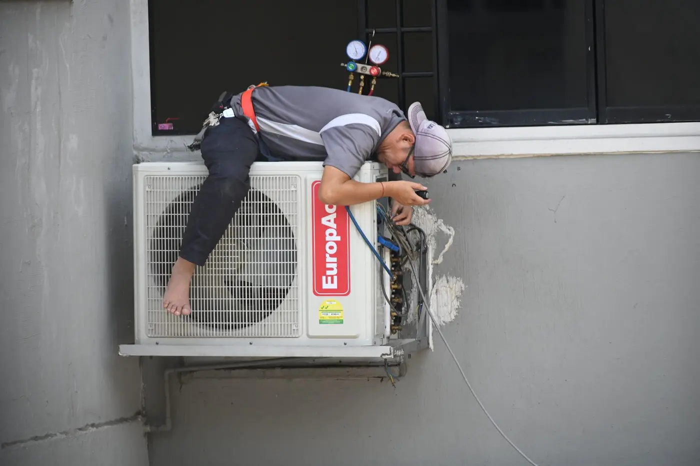 Technician working inside the wiring compartment of a wall-mounted outdoor air conditioner