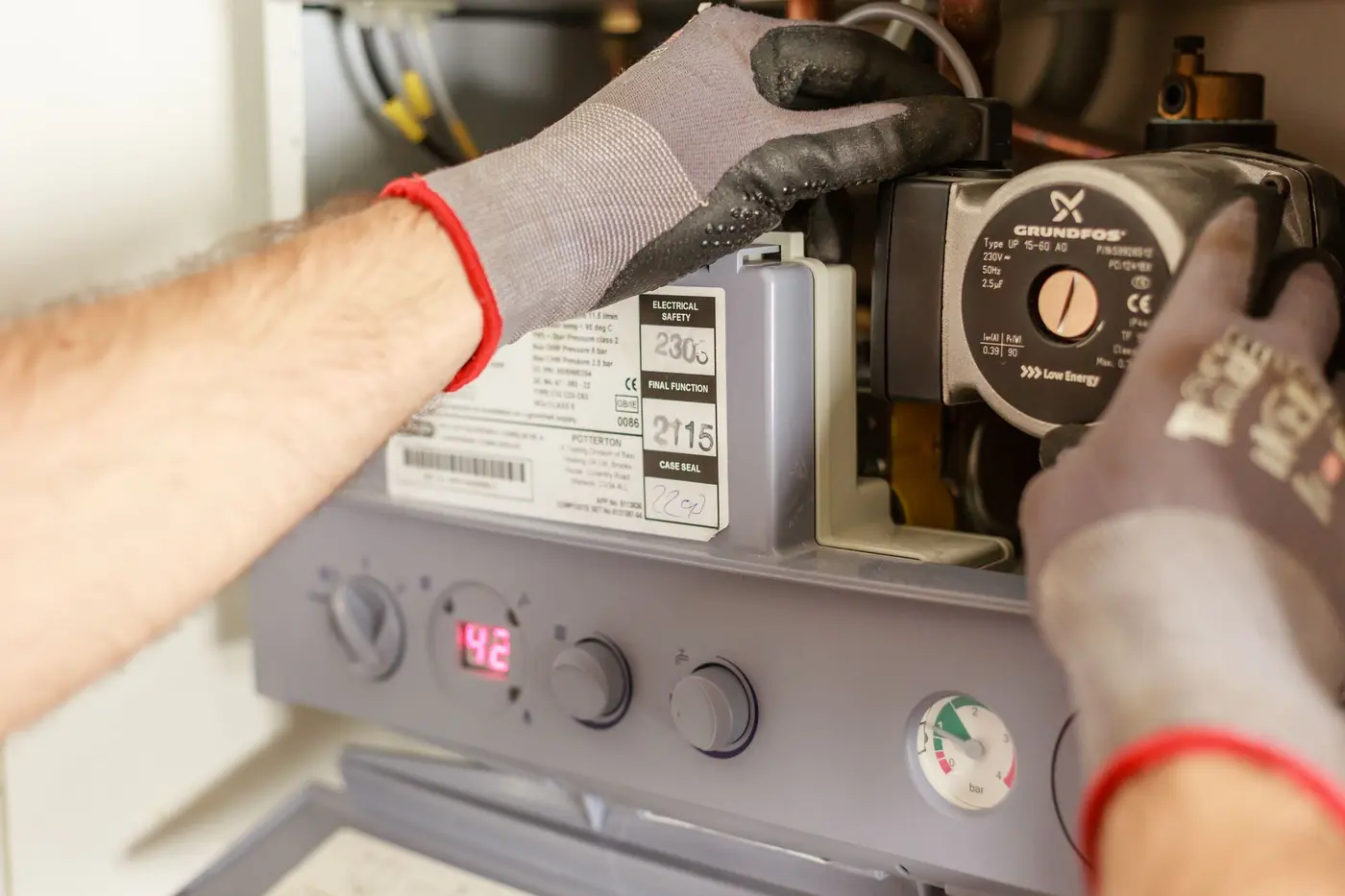 Technician adjusting the gauges and controls on a boiler during a service visit