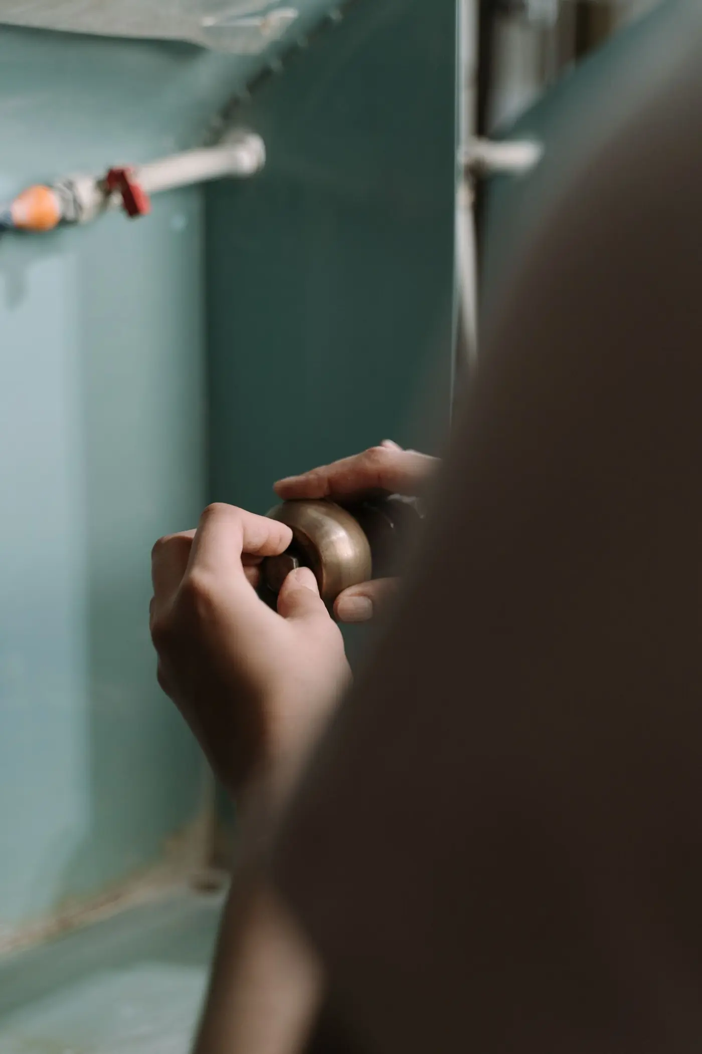 Hands adjusting the drain trap under a kitchen sink