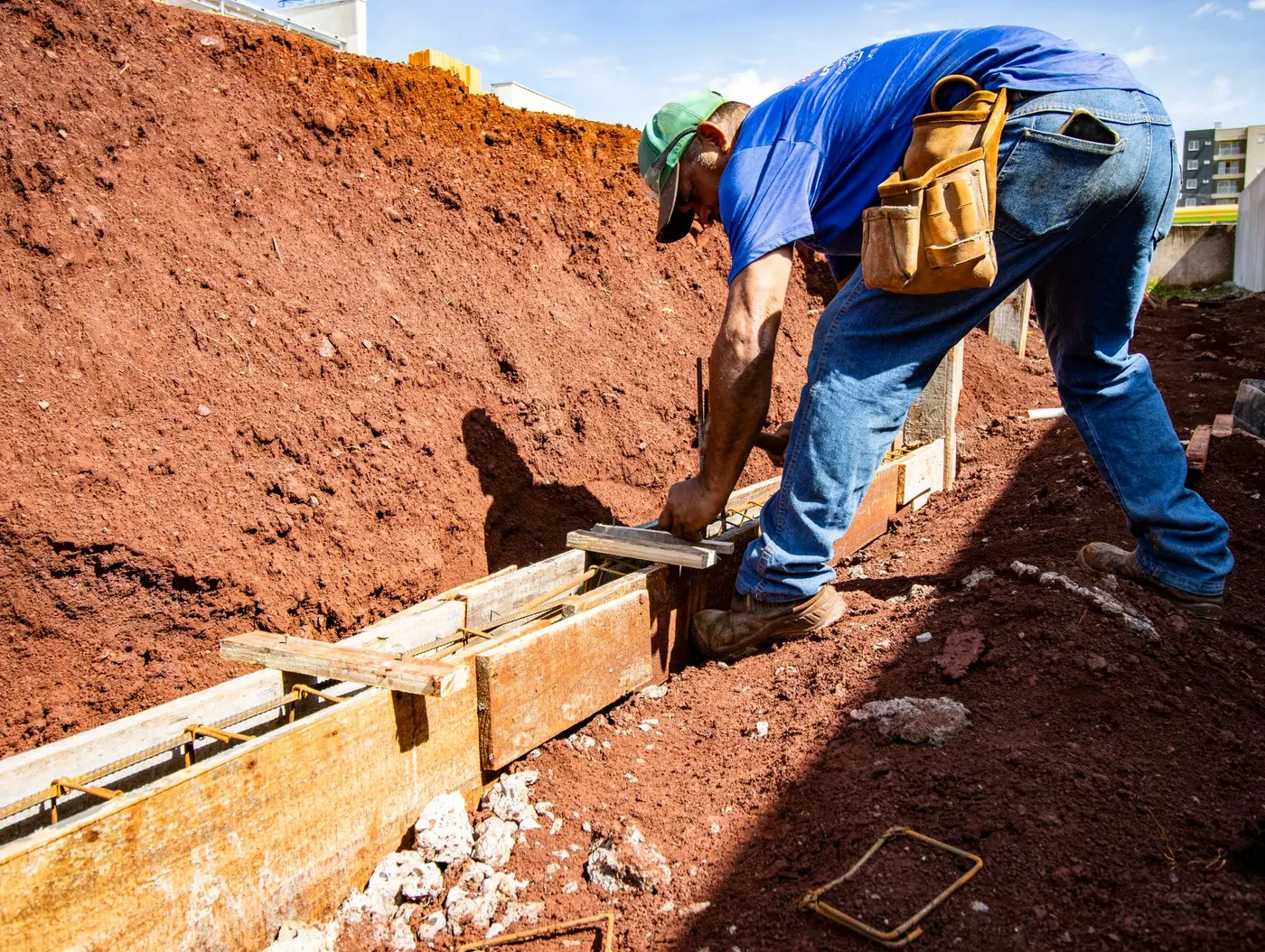 Worker at ground level doing exterior foundation and drainage work