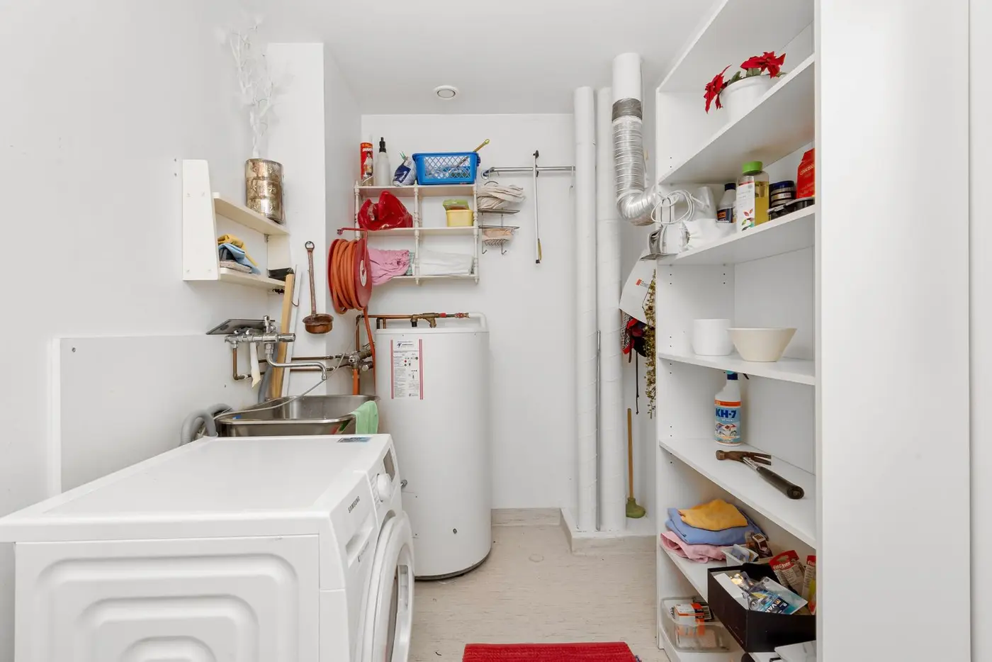 Home utility room with a water heater tank and laundry plumbing